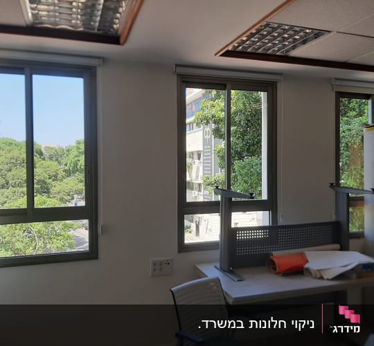 חדר עם שולחן הפוך, חלונות גדולים ועצים בחוץ